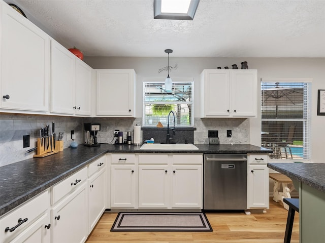 11823 Elizabeth Ct, Pinehurst, TX 77362 - kitchen featuring stainless steel dishwasher, a sink, white cabinets, light wood-type flooring, and a textured ceiling