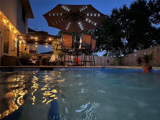 11823 Elizabeth Ct, Pinehurst, TX 77362 - pool at twilight with a fenced backyard and a patio