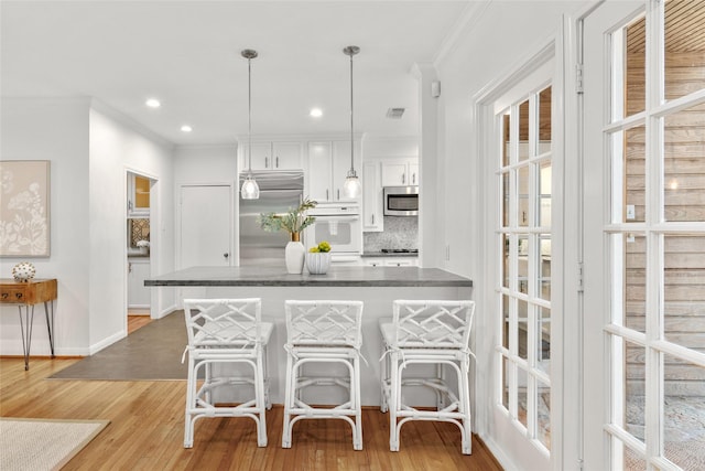 3803 Sunset Blvd, West University Place, TX 77005 - kitchen with stainless steel appliances, white cabinetry, crown molding, a breakfast bar area, and tasteful backsplash