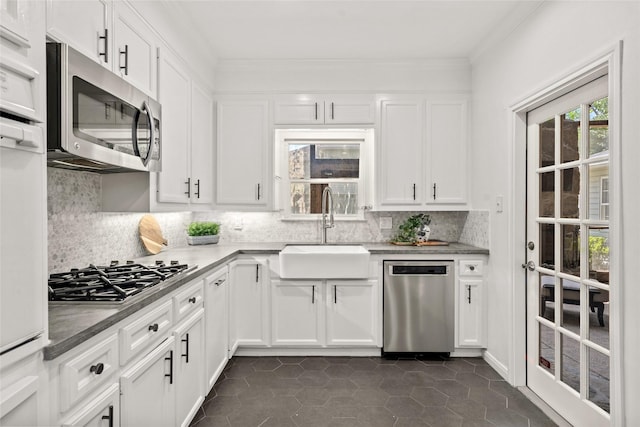 3803 Sunset Blvd, West University Place, TX 77005 - kitchen featuring appliances with stainless steel finishes, a sink, decorative backsplash, white cabinetry, and dark tile patterned floors