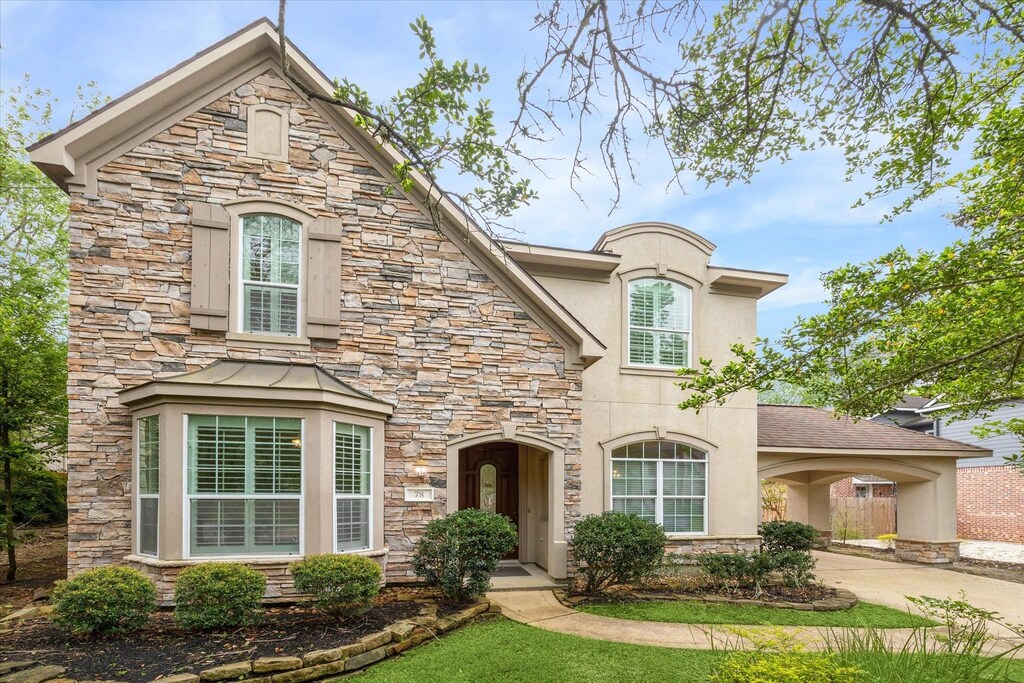 french country style house with stone siding, concrete driveway, and stucco siding