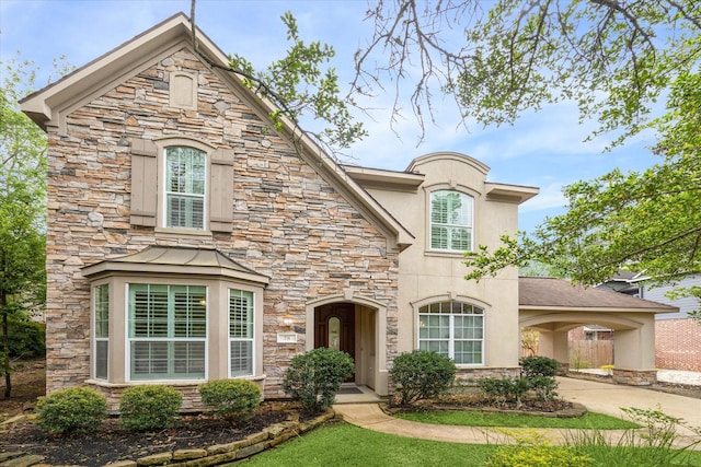 french country style house with stone siding, concrete driveway, and stucco siding