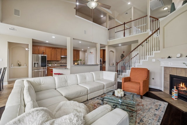 15314 Ashbrook Dove Ln, Cypress, TX 77429 - living room featuring a high ceiling, baseboards, ceiling fan, stairway, and a tile fireplace