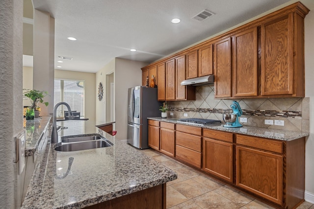 15314 Ashbrook Dove Ln, Cypress, TX 77429 - kitchen with a sink, appliances with stainless steel finishes, under cabinet range hood, decorative backsplash, and brown cabinetry