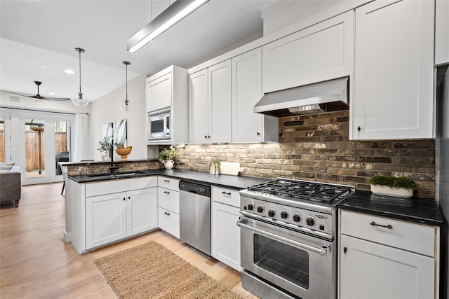 1728 Nicholson St, Houston, TX 77008 - kitchen with appliances with stainless steel finishes, wall chimney range hood, a sink, a peninsula, and tasteful backsplash