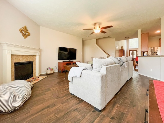 20223 Benton Springs Ln, Richmond, TX 77407 - living area with a ceiling fan, dark wood finished floors, a tiled fireplace, stairway, and baseboards