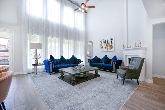 3207 Sweet Audrey Ln, Richmond, TX 77406 - living room featuring a towering ceiling, ceiling fan, wood finished floors, baseboards, and arched walkways