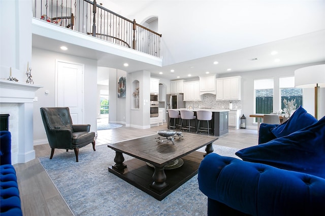 3207 Sweet Audrey Ln, Richmond, TX 77406 - living room featuring a fireplace, a towering ceiling, light wood finished floors, baseboards, and recessed lighting
