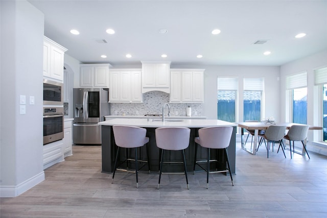 3207 Sweet Audrey Ln, Richmond, TX 77406 - kitchen featuring appliances with stainless steel finishes, a sink, a center island with sink, backsplash, and light countertops