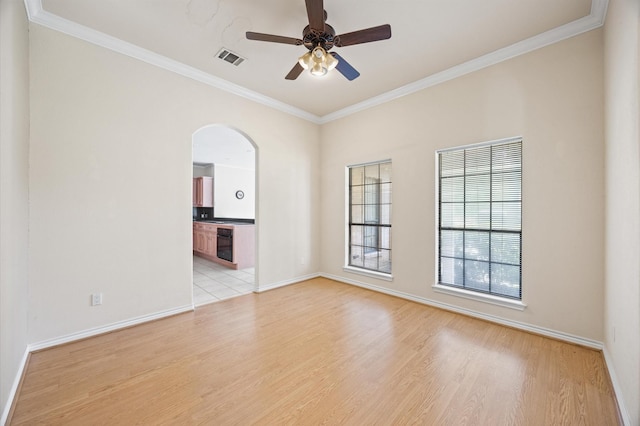 25187 Hill And Dale Ave, Splendora, TX 77372 - spare room featuring light wood-style floors, ornamental molding, ceiling fan, arched walkways, and baseboards