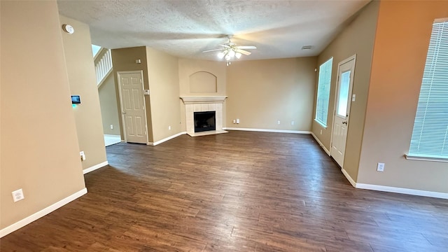 19646 Ballina Meadows Dr, Katy, TX 77449 - unfurnished living room featuring ceiling fan, dark wood-style flooring, baseboards, a tiled fireplace, and a textured ceiling