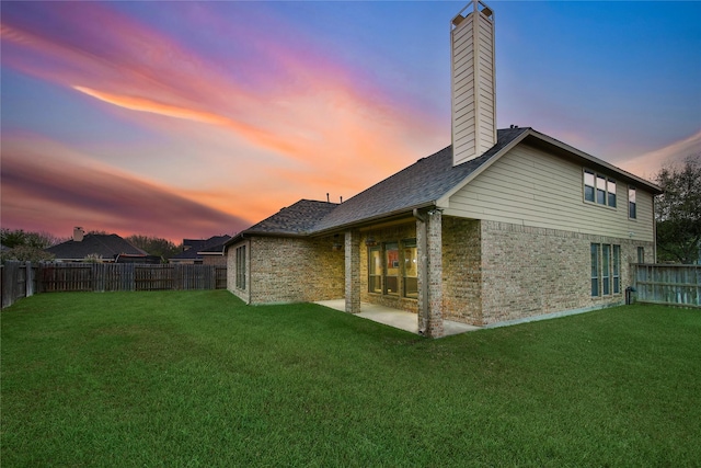 12119 Bayou Junction Rd, Cypress, TX 77433 - back of house at dusk featuring brick siding, a chimney, and a patio