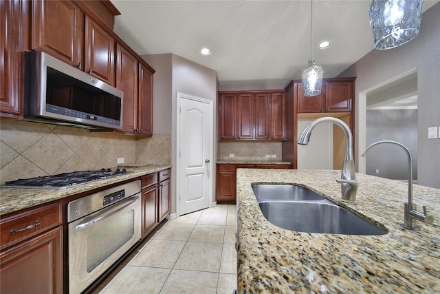 12119 Bayou Junction Rd, Cypress, TX 77433 - kitchen featuring appliances with stainless steel finishes, a sink, pendant lighting, light stone countertops, and backsplash