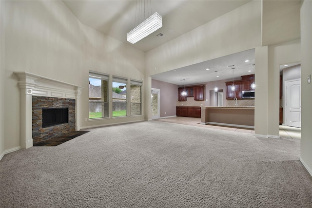 12119 Bayou Junction Rd, Cypress, TX 77433 - unfurnished living room featuring light colored carpet, a high ceiling, baseboards, a sink, and a fireplace