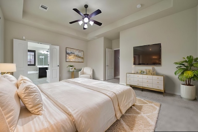 12119 Bayou Junction Rd, Cypress, TX 77433 - bedroom with a tray ceiling, connected bathroom, baseboards, a ceiling fan, and light carpet