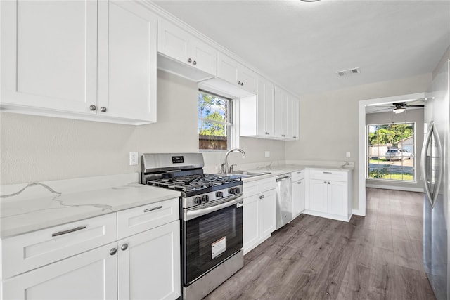 9110 Vickijohn Dr, Houston, TX 77031 - kitchen with stainless steel appliances, a sink, wood finished floors, white cabinets, and light stone counters