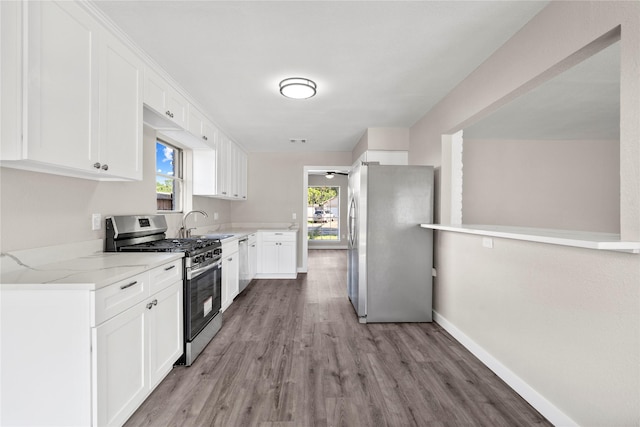9110 Vickijohn Dr, Houston, TX 77031 - kitchen featuring appliances with stainless steel finishes, light wood-style floors, white cabinetry, light stone counters, and baseboards