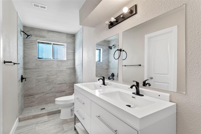 9110 Vickijohn Dr, Houston, TX 77031 - bathroom featuring a tile shower, toilet, double vanity, and a textured wall