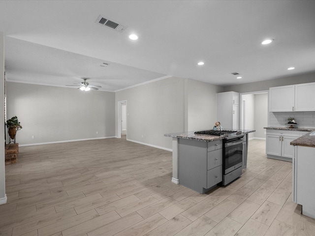 618 Forest Lake Dr, Seabrook, TX 77586 - kitchen with stainless steel gas range, light wood-style flooring, dark stone countertops, ceiling fan, and crown molding