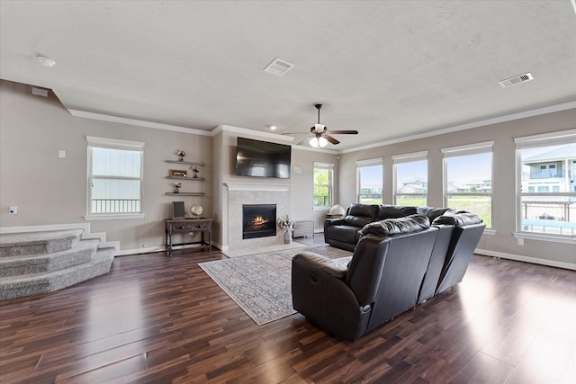 10744 S Lake Mist Ln, Willis, TX 77318 - living room with dark wood-type flooring, healthy amount of natural light, crown molding, ceiling fan, and a tiled fireplace