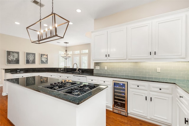 5819 Desert Oak Way, Spring, TX 77379 - kitchen with wine cooler, a chandelier, black gas cooktop, a sink, and wood finished floors