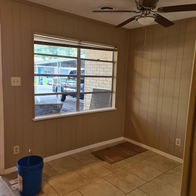1229 Ramona St, Angleton, TX 77515 - empty room featuring a ceiling fan, light tile patterned floors, baseboards, and wood walls