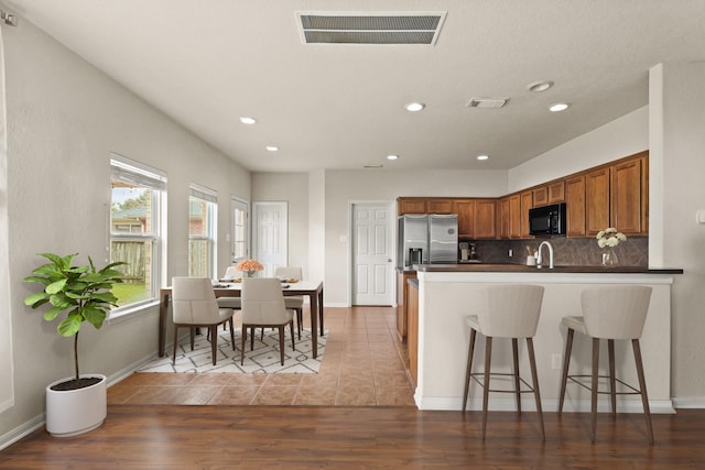 6010 Twin Crk, Missouri City, TX 77459 - kitchen featuring black microwave, stainless steel refrigerator with ice dispenser, a peninsula, recessed lighting, and brown cabinetry