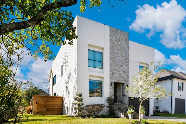 4301 Vivian St, Bellaire, TX 77401 - view of home's exterior featuring stone siding, a yard, driveway, and a garage