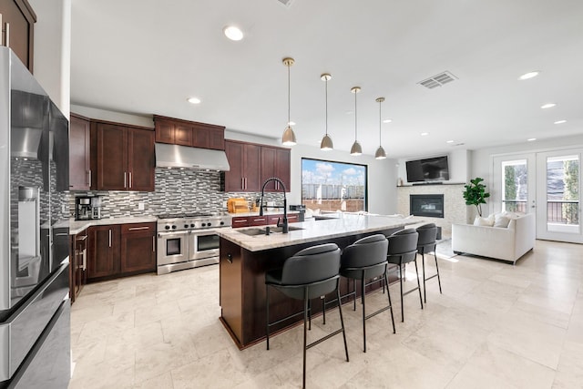 4301 Vivian St, Bellaire, TX 77401 - kitchen with range with two ovens, refrigerator with ice dispenser, under cabinet range hood, a sink, and tasteful backsplash