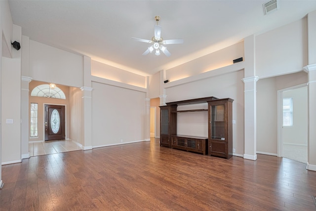 11606 Canyon Breeze Dr, Tomball, TX 77377 - unfurnished living room featuring a towering ceiling, a ceiling fan, decorative columns, hardwood / wood-style flooring, and baseboards