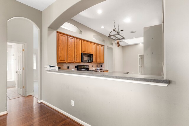 10446 Antelope Aly, Missouri City, TX 77459 - kitchen with black appliances, decorative backsplash, wood finished floors, arched walkways, and recessed lighting
