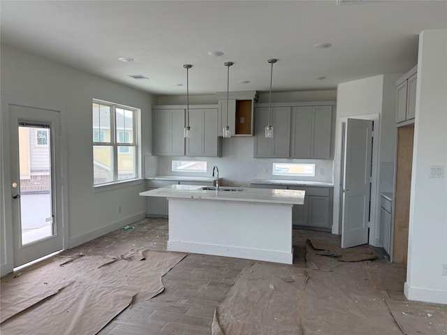 15867 Invergelder Dr, Atascocita, TX 77346 - kitchen with gray cabinetry, an island with sink, tasteful backsplash, and decorative light fixtures
