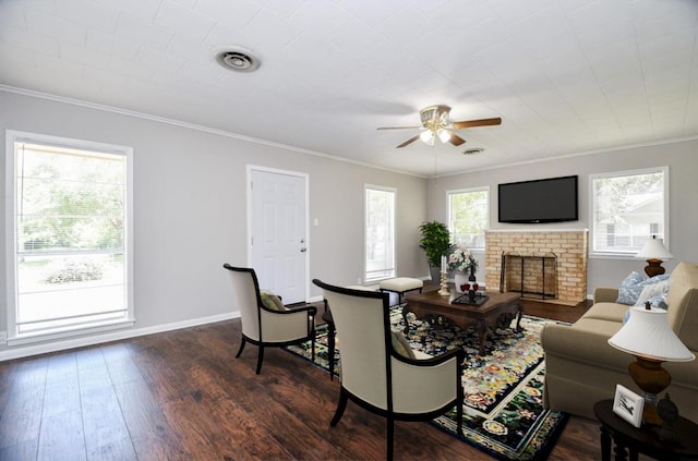 1225 Kirsten St, Galveston, TX 77568 - living room featuring a brick fireplace, crown molding, a ceiling fan, dark wood-style flooring, and baseboards