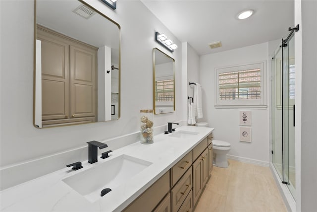 full bath featuring a stall shower, toilet, double vanity, and baseboards