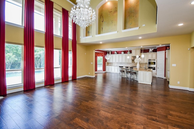 5450 Pudman River Ln, Sugar Land, TX 77479 - unfurnished living room with a chandelier, healthy amount of natural light, baseboards, recessed lighting, and a high ceiling