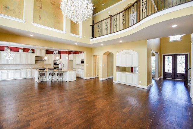 5450 Pudman River Ln, Sugar Land, TX 77479 - unfurnished living room featuring a high ceiling, a chandelier, baseboards, dark wood-style flooring, and a sink