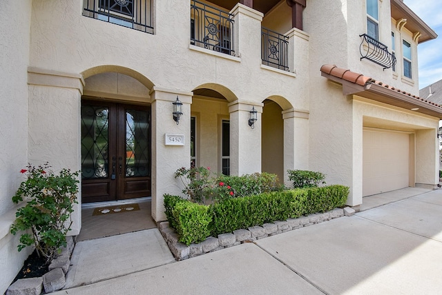 5450 Pudman River Ln, Sugar Land, TX 77479 - property entrance with french doors, a garage, stucco siding, driveway, and a balcony