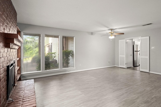 7736 Challie Ln, Houston, TX 77088 - unfurnished living room featuring a brick fireplace, ceiling fan, wood finished floors, and baseboards