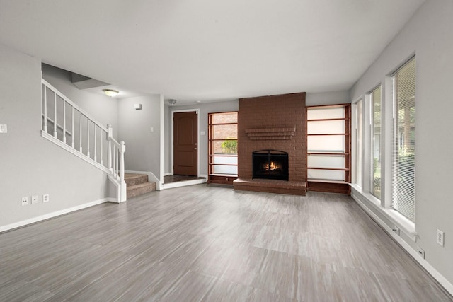 7736 Challie Ln, Houston, TX 77088 - unfurnished living room with a brick fireplace, baseboards, wood finished floors, and stairs