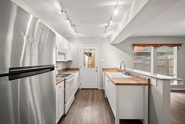 7736 Challie Ln, Houston, TX 77088 - kitchen featuring white appliances, a sink, a peninsula, track lighting, and dark wood-type flooring