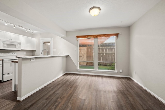 7736 Challie Ln, Houston, TX 77088 - kitchen featuring white appliances, white cabinetry, dark wood-type flooring, and baseboards