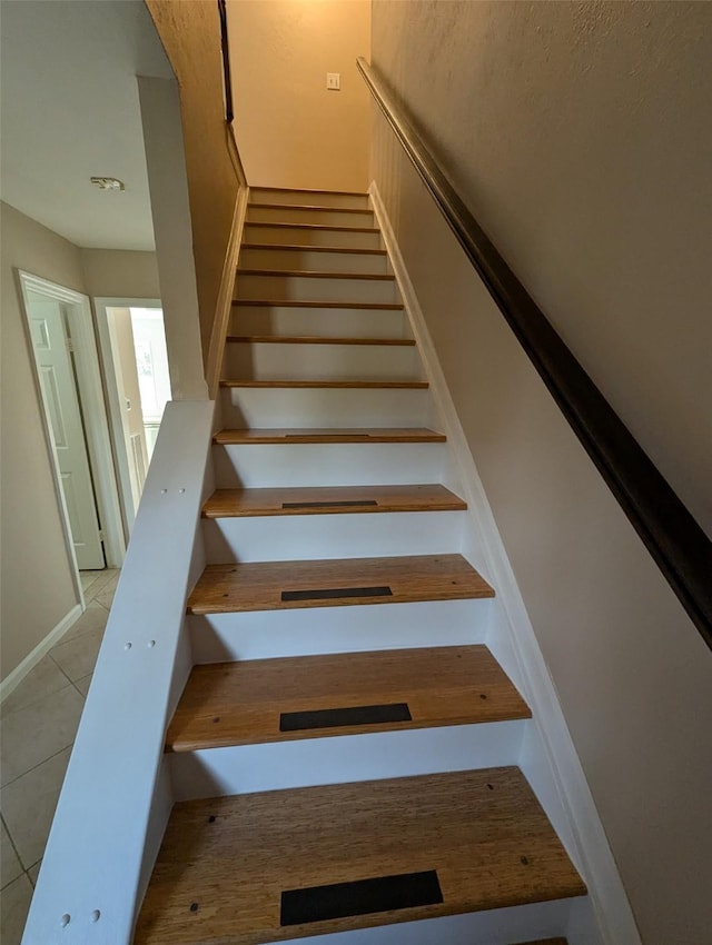 staircase featuring tile patterned floors and baseboards