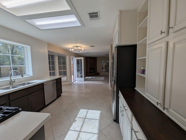 kitchen featuring appliances with stainless steel finishes, open shelves, a sink, open floor plan, and light tile patterned flooring