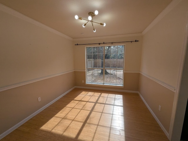 empty room with a chandelier, wood finished floors, baseboards, and ornamental molding