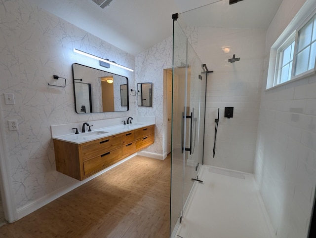 full bathroom featuring vaulted ceiling, a stall shower, double vanity, and baseboards