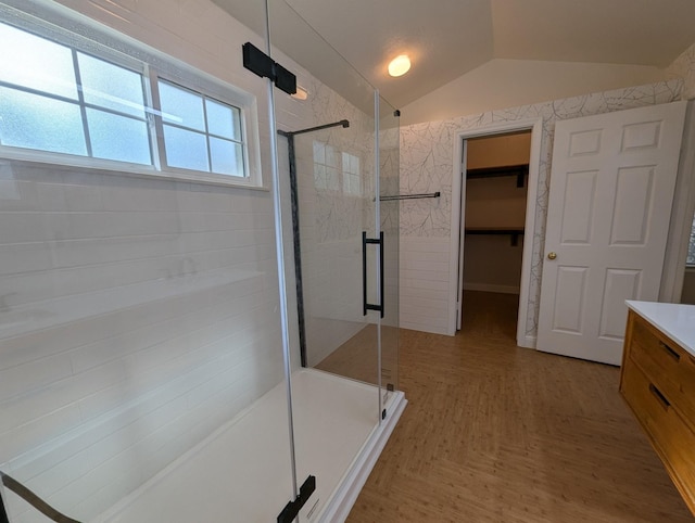 full bath with a stall shower, lofted ceiling, a spacious closet, and vanity