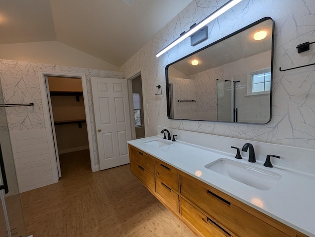 bathroom with lofted ceiling, a stall shower, a spacious closet, and double vanity