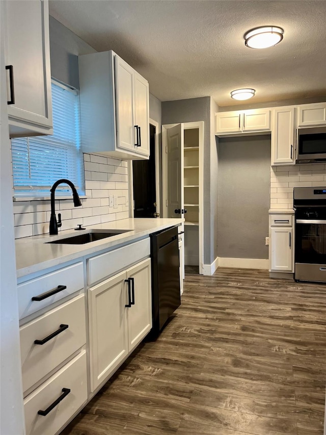 6107 Belmark St, Houston, TX 77033 - kitchen featuring appliances with stainless steel finishes, a sink, backsplash, baseboards, and white cabinetry