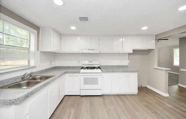 720 Roosevelt St, La Marque, TX 77568 - kitchen with white range with gas cooktop, under cabinet range hood, a sink, light wood-style floors, and white cabinets
