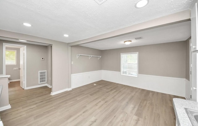 720 Roosevelt St, La Marque, TX 77568 - basement featuring a textured ceiling, light wood-type flooring, wainscoting, plenty of natural light, and a sink